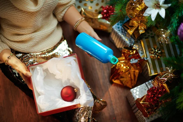 在装饰过的圣诞树下 穿着金色紧身衣和白色毛衣的时髦家庭主妇们站在装有圣诞礼盒和可重复使用的健身水瓶的礼盒旁边 — 图库照片