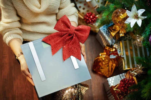 穿着金色紧身衣裙和白色毛衣的时髦女人的衣服 在装饰过的圣诞树下靠近礼物盒的地方露出红色蝴蝶结的鳞片 — 图库照片