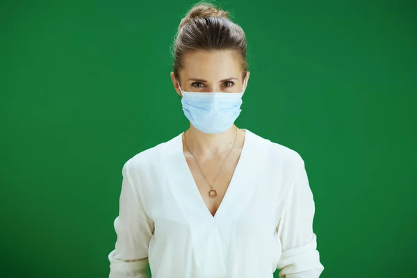 在大肠病毒大流行期间的生命 浅谈现代中年妇女教师白衬衫 绿底医用面罩的画像 — 图库照片
