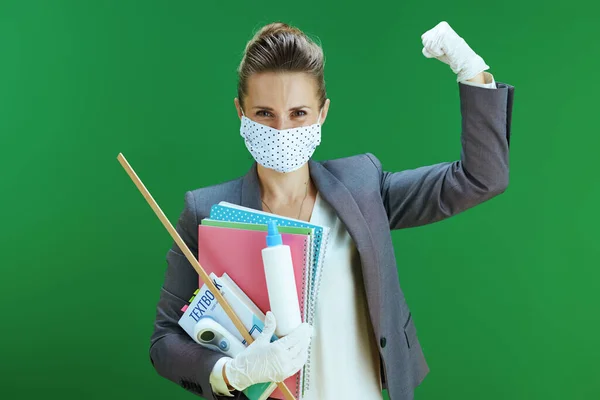 穿着白衬衫的现代女教师 戴着医疗面罩 橡胶手套 数字温度计 课本和一种抗菌药物 在黑板绿色上显示出二头肌隔离 — 图库照片