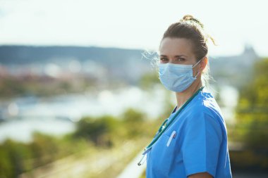 Covid-19 salgını. Şehir sokaklarında steteskop ve maske takmış modern kadın doktorların portresi..