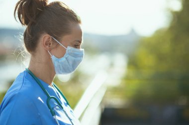 Covid-19 salgını. Steteskop ve tıbbi maskeli, üniformalı, modern tıbbi pratisyen kadın..