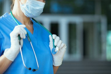 Koronavirüs salgını. Kliniğin dışında steteskop ve tıbbi maske takan üniformalı kadın doktorlara yakın çekim..