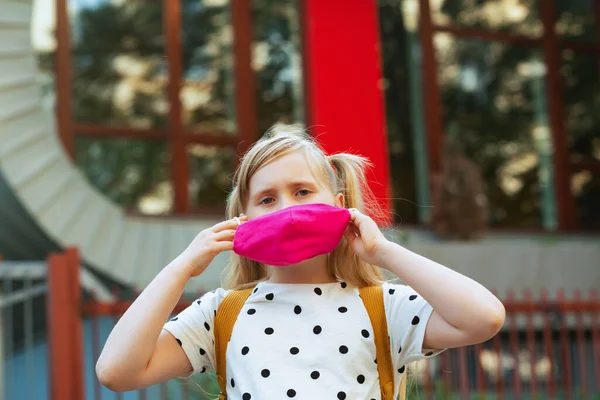 Covid-19 salgını sırasında hayat. Beyaz benekli bluzlu, pembe maskeli, okul çıkışlı, modern okul kızı..