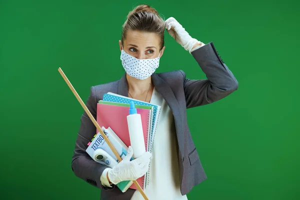 在大肠病毒大流行期间的生命 穿着白衬衫 戴着医疗面罩 橡胶手套 数字温度计 课本和在黑板绿色上隔离的抗菌药物的沉思的现代女教师 — 图库照片