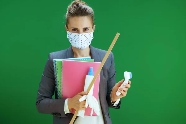 在大肠病毒大流行期间的生命 现代中年女教师 身穿白衬衫 戴着医疗面罩 橡胶手套 数字温度计和卫生设备 隔离在黑板绿色中 — 图库照片