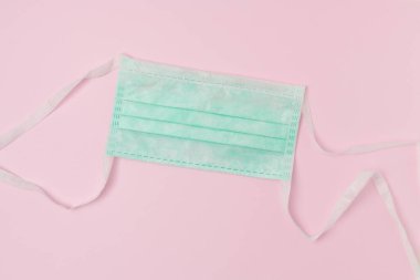 Koronavirüs düz ve pembe arka planda tıbbi maske var..