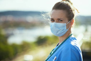 Covid-19 salgını. Şehir sokaklarında, üniformalı, tıbbi maskeli, modern doktor portresi..