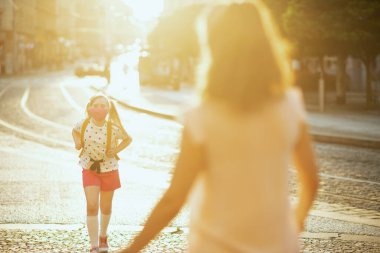 Koronavirüs salgını sırasında hayat. Maskeli modern anne ve çocuk okuldan çıkıyorlar..
