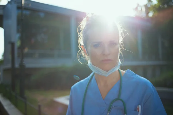 验尸官大流行病 近门诊部外穿着制服 戴听诊器 戴口罩的紧张现代女医生的画像 — 图库照片