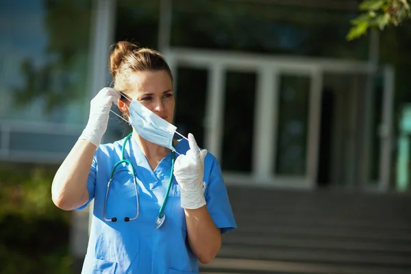 验尸官大流行病 在医院附近的室外用听诊器和医疗面罩擦拭的现代医生妇女 — 图库照片