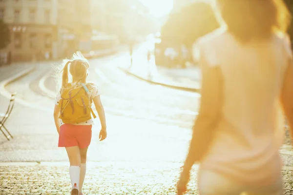 在大肠病毒大流行期间的生命 从现代母亲和女儿身后看到 他们背着黄色的背包去外面上学 — 图库照片
