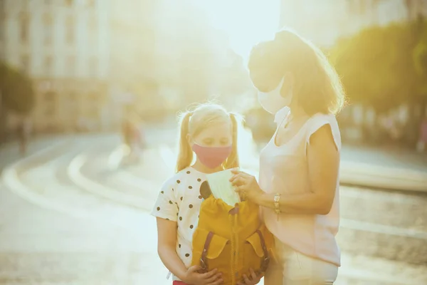 코로나 바이러스가 유행하는 동안의 학교갈 준비를 가방에 의료용 마스크를 어머니와 — 스톡 사진