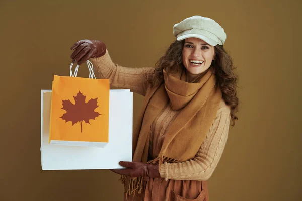 10月だ スタイリッシュな40歳の女性を笑顔でスカーフで革手袋と紙のショッピングバッグでベージュの背景 — ストック写真