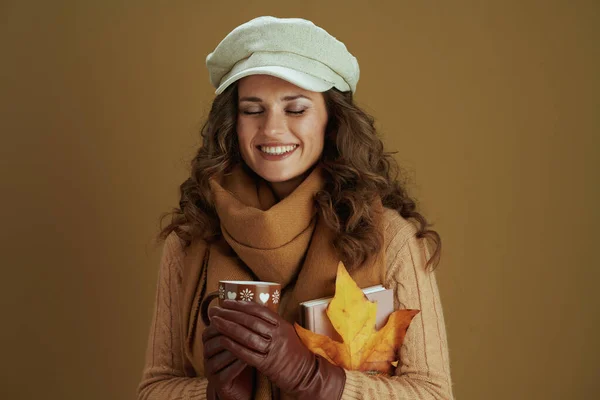 十一月 穿着黄色秋天枫叶 皮手套和杯子的毛衣的时髦女人 与米黄色隔离 — 图库照片