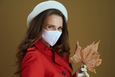 Merhaba sonbahar. Sarı sonbahar akçaağaç yaprağı ve kahverengi arka planda kırmızı ceketli orta yaşlı ev kadınının portresi..