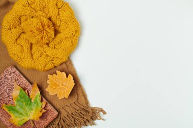 Merhaba sonbahar. Beyaz zemin üzerinde eşarp, şapka, yapraklar, defter ve mum ile sonbahar düz yatıyordu.
