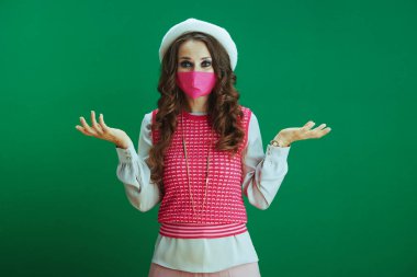 Covid-19 salgını sırasında hayat. Kafası karışmış, pembe kolsuz gömlekli, yeşil maskeli zarif bir kadın..