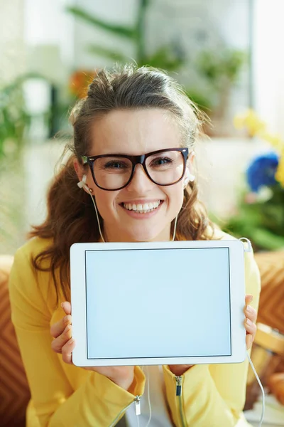 Portret Uśmiechniętej Młodej Gospodyni Domowej Żółtej Kurtce Słuchawkami Pokazującymi Tablet — Zdjęcie stockowe