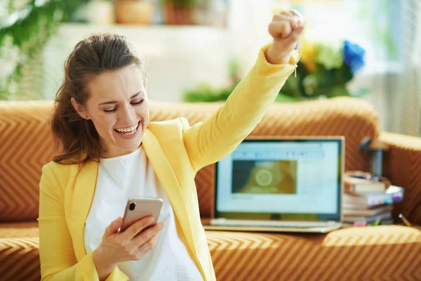 Szczęśliwa Elegancka Kobieta Żółtej Kurtce Laptopem Smartfonem Raduje Się Podczas — Zdjęcie stockowe