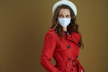 Merhaba sonbahar. Bronz arka planda izole edilmiş kırmızı ceketli düşünceli bir kadın..