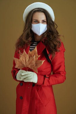 Covid-19 salgını sırasında hayat. Kırk yaşında, kırmızı ceketli, sarı sonbahar akçaağaç yaprağıyla bronz arka planda dalgın bir ev hanımı..