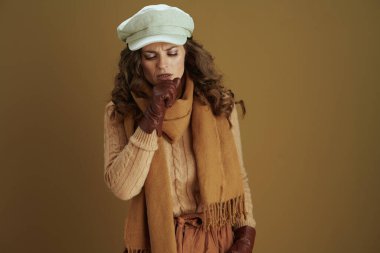 Merhaba Eylül. Kahverengi arka planda deri eldivenli modern orta yaşlı ev hanımı..