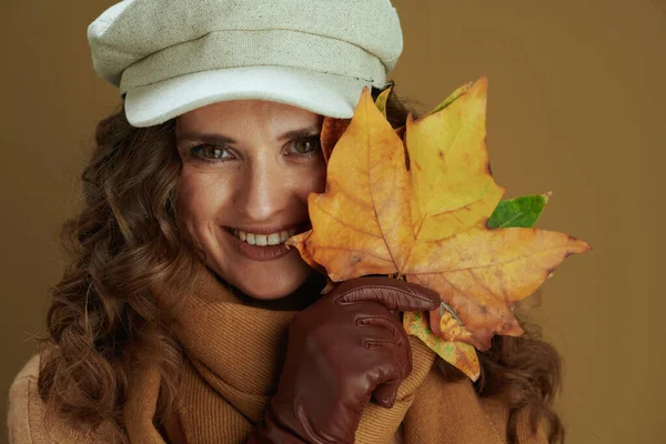 幸せなトレンディーな中年主婦の肖像でセーターで革手袋と黄色の紅葉茶色の背景に隔離された葉 — ストック写真