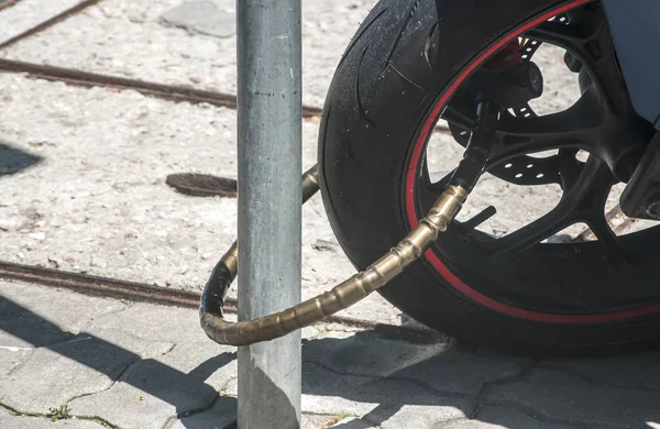 Güçlü motosiklet zincir bisiklet kilidi yol işaret direği closeup için güneşli bir günde mi kilitledin arka tekerlek