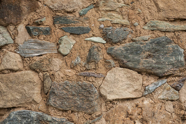 Old grunge weathered stone wall of rural farm house closeup as background