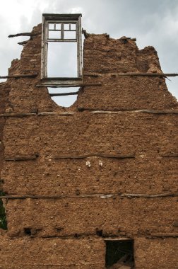 Tuğla duvar adobe kil sıva ve kırık ahşap pencere çerçeve ile harap eski kırsal ülke evin bulutlu mavi gökyüzü arka plan üzerinde kaldı