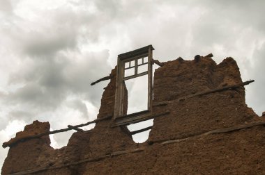 Tuğla duvar adobe kil sıva ve kırık ahşap pencere çerçeve ile harap eski kırsal ülke evin bulutlu mavi gökyüzü arka plan üzerinde kaldı