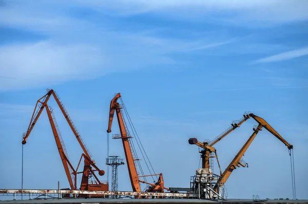 Industrial scene with river port crane facilities on blue sky background