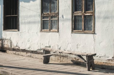 Güneşli bir gün içinde yıpranmış ahşap pencereler ve tezgah ile eski kır evi cephe