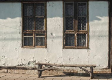 Güneşli bir gün içinde yıpranmış ahşap pencereler ve tezgah ile eski kır evi cephe