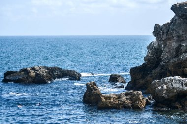 Yazın mavi suları ve kıyı kayalarıyla kıyı manzarası
