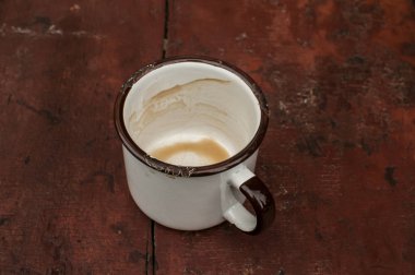 Boyalı grunge kurulları yüzey eski masada kahve içeceği kalıntıları ile Metal emaye kupa