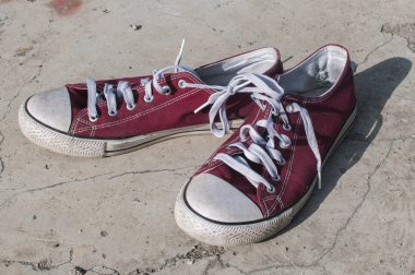 Dış beton yüzeyinde yıpranmış vintage kırmızı eski tuval spor ayakkabı çifti