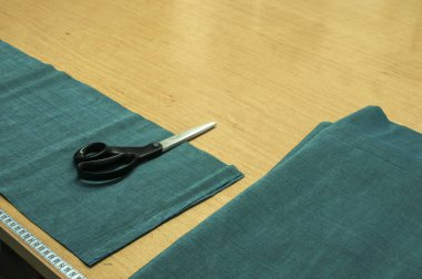 Makas, santimetrelik cetvel ve dikiş atölyesinde masada kumaş kesme için hazırlanmış