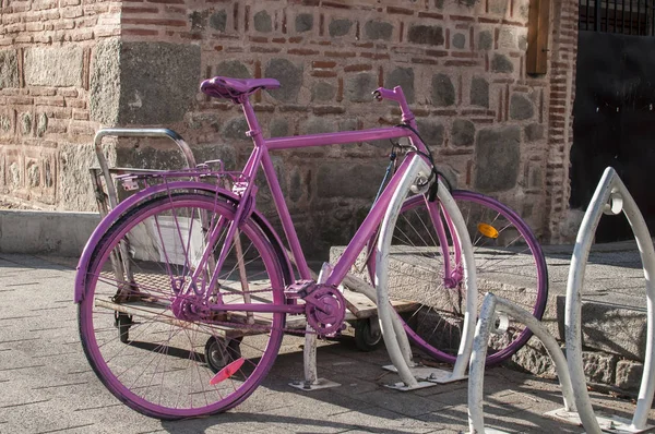 Pink painted bicycle locked on bike stand