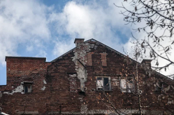 青空の背景に大きな木の枝の後ろに古い放棄された建物のファサード — ストック写真