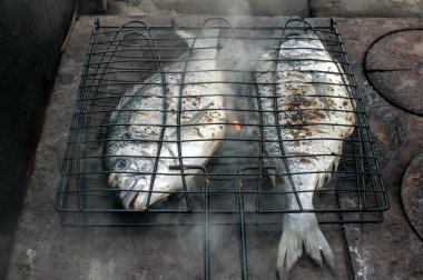 Demir ocakta ızgarada kızartılmış, yaldızlı balık.