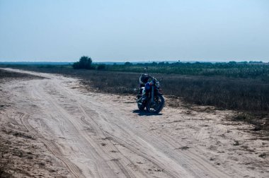 Motorsiklet güneşli yaz gününde terk edilmiş kumlu yolda durdu.