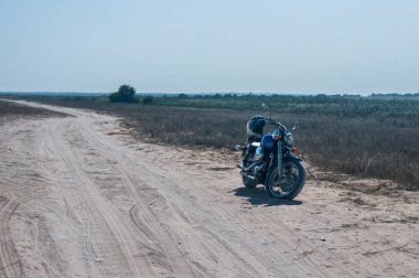 Motorsiklet güneşli yaz gününde terk edilmiş kumlu yolda durdu.