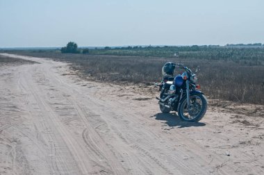 Motorsiklet güneşli yaz gününde terk edilmiş kumlu yolda durdu.