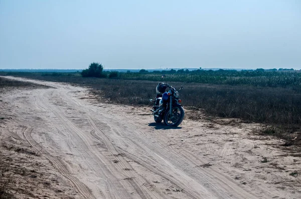 Motorsiklet güneşli yaz gününde terk edilmiş kumlu yolda durdu.