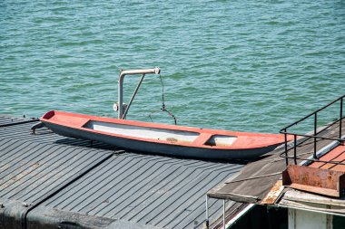 Ağır paslanmış eski bir nehir mavnası. İhmal edilmiş bir sanayi limanındaki giriş platformuna demirlemiş.