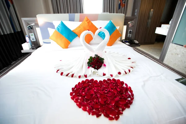 Towel folding in white bed for decoration look like heart or swan with red Petals rose heart shape