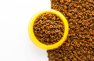 Beyaz arka planda izole edilmiş kuru köpek mamasıyla dolu sarı plastik kase. Yazı dizaynının kopyası olan en iyi tahıllı evcil hayvan yiyeceği. Üst ya da Üst Manzara. yiyecek dokusu pankartı