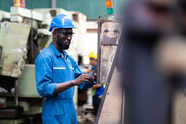 Siyah Erkek Mühendis Fabrika 'da makine üzerinde çalışıyor. Makinenin durumunu kontrol eden siyah adam mühendisi. Fabrika makinelerinin bakım ve onarımı. Amerikan Afrikalıları.